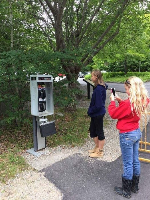 Kids taking photo of a pay phone